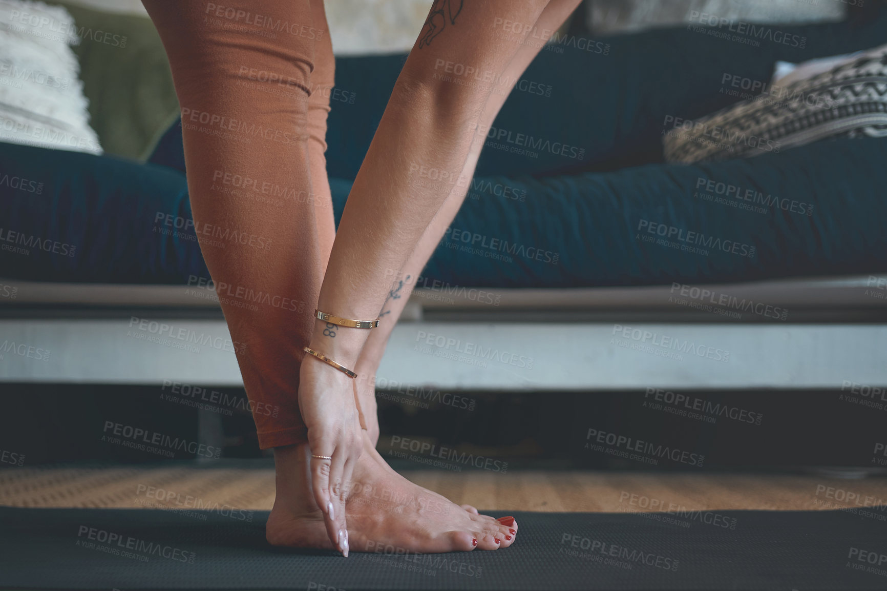Buy stock photo Closeup shot of an unrecognisable woman touching her toes while exercising at home