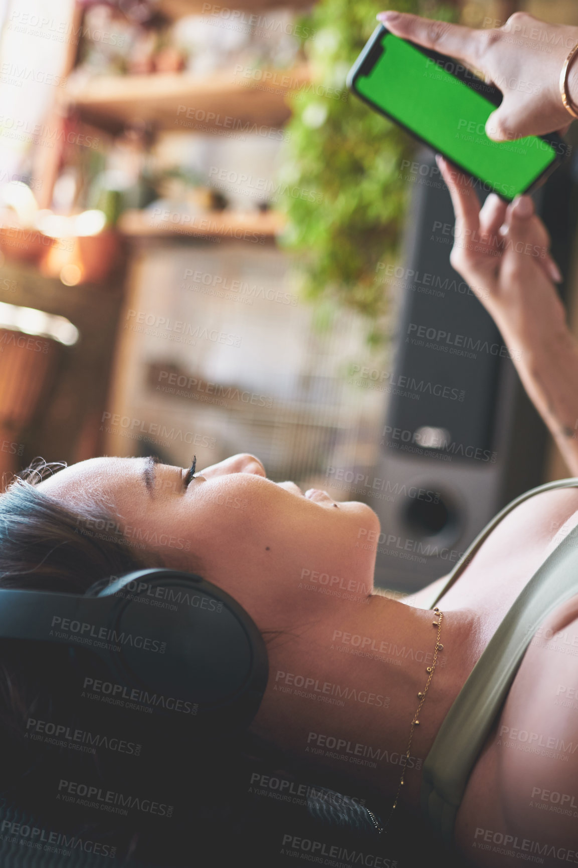 Buy stock photo Shot of a young woman wearing headphones and using a cellphone while lying on an exercise mat at home