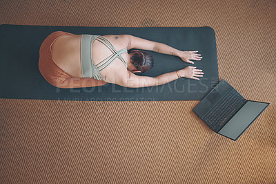 Buy stock photo High angle shot of a young woman using a laptop while practising yoga at home