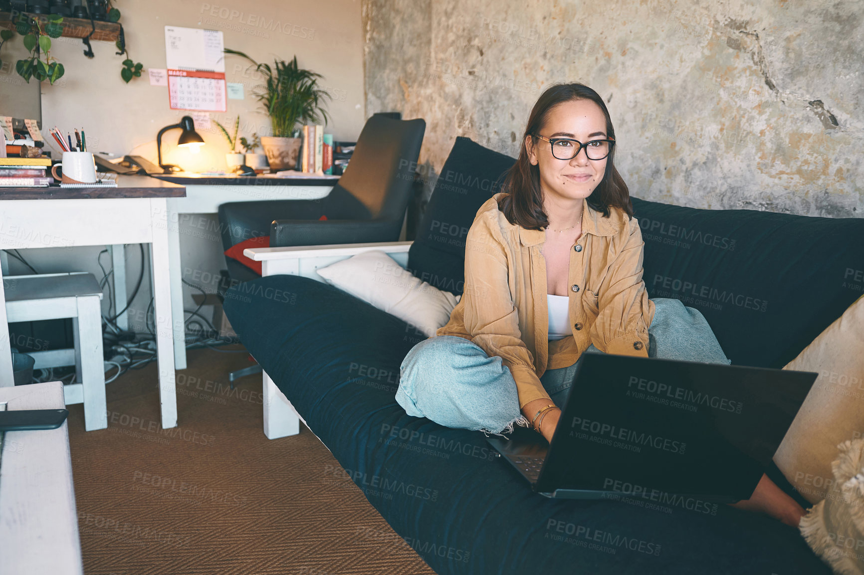 Buy stock photo Shot of a young woman using a laptop on the sofa at home