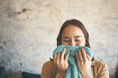 Buy stock photo Shot of a young woman smelling freshly washed laundry at home