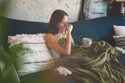 Buy stock photo Shot of a young woman suffering from a headache and feeling sick on the sofa at home