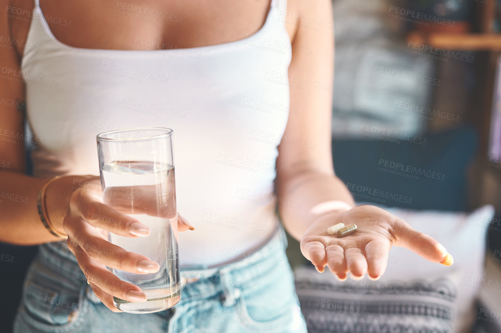 Buy stock photo Shot of an unrecognisable woman taking a pill with a glass of water at home