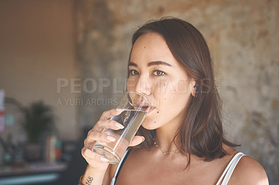 Buy stock photo Shot of a young woman drinking a glass of water at home