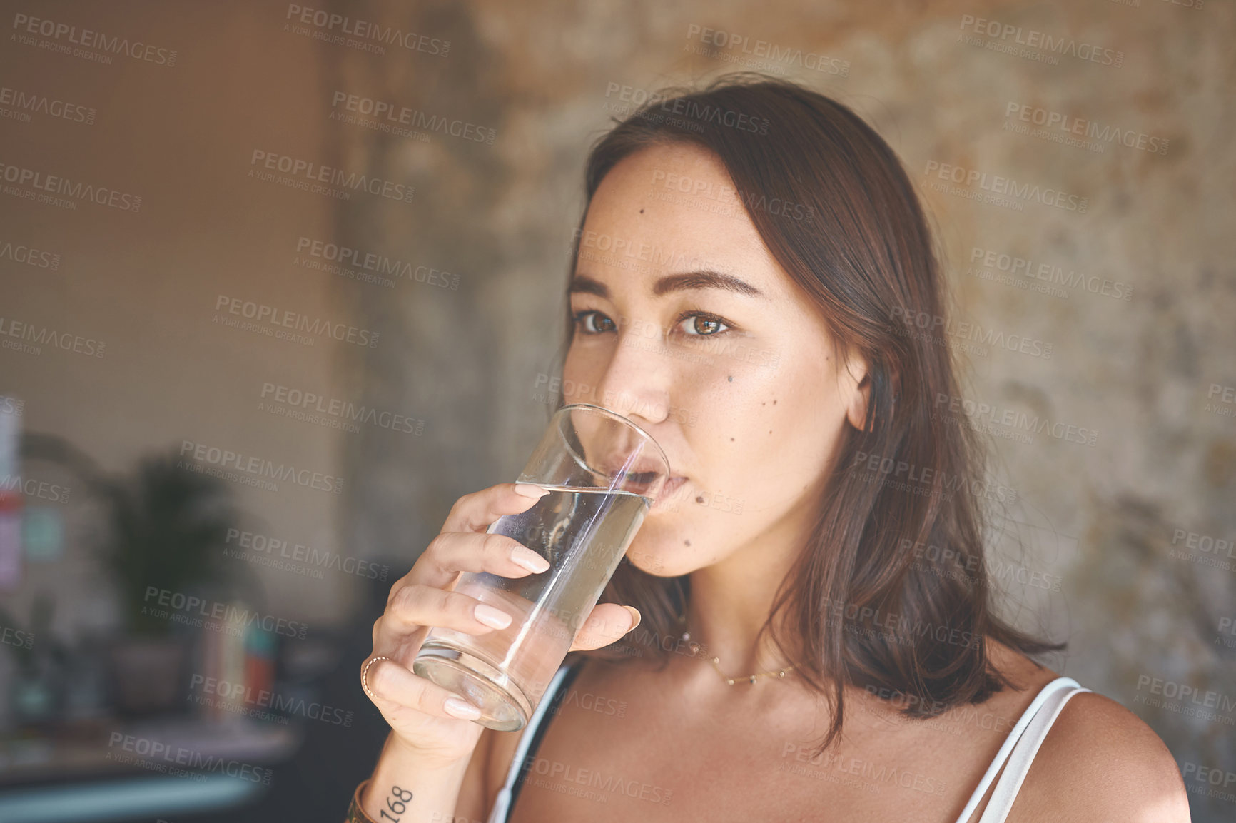 Buy stock photo Shot of a young woman drinking a glass of water at home