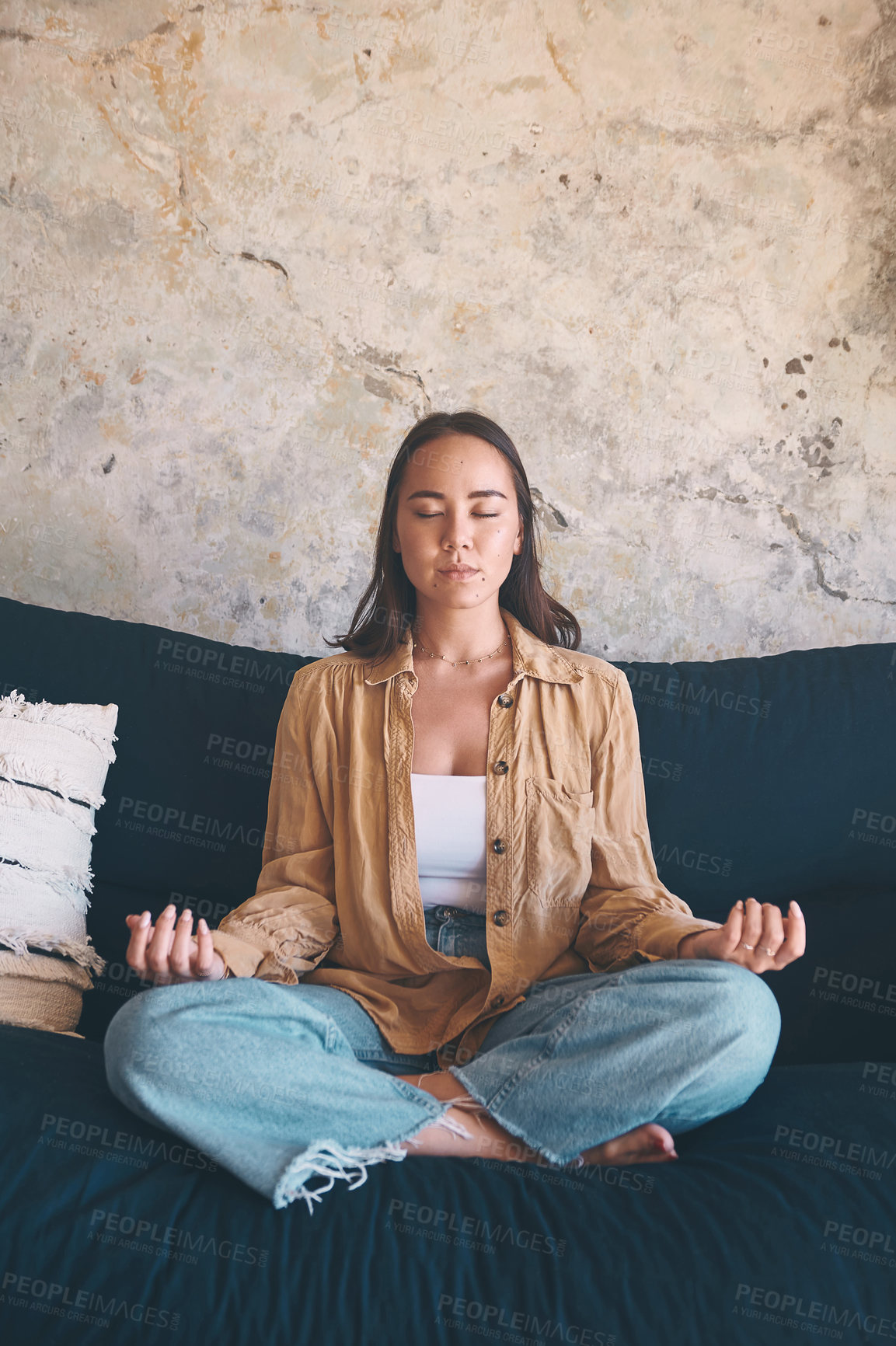 Buy stock photo Shot of a young woman meditating on the sofa at home