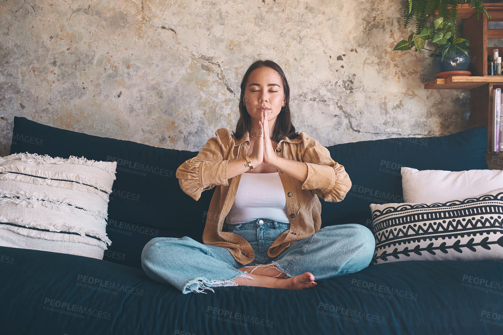 Buy stock photo Shot of a young woman meditating on the sofa at home