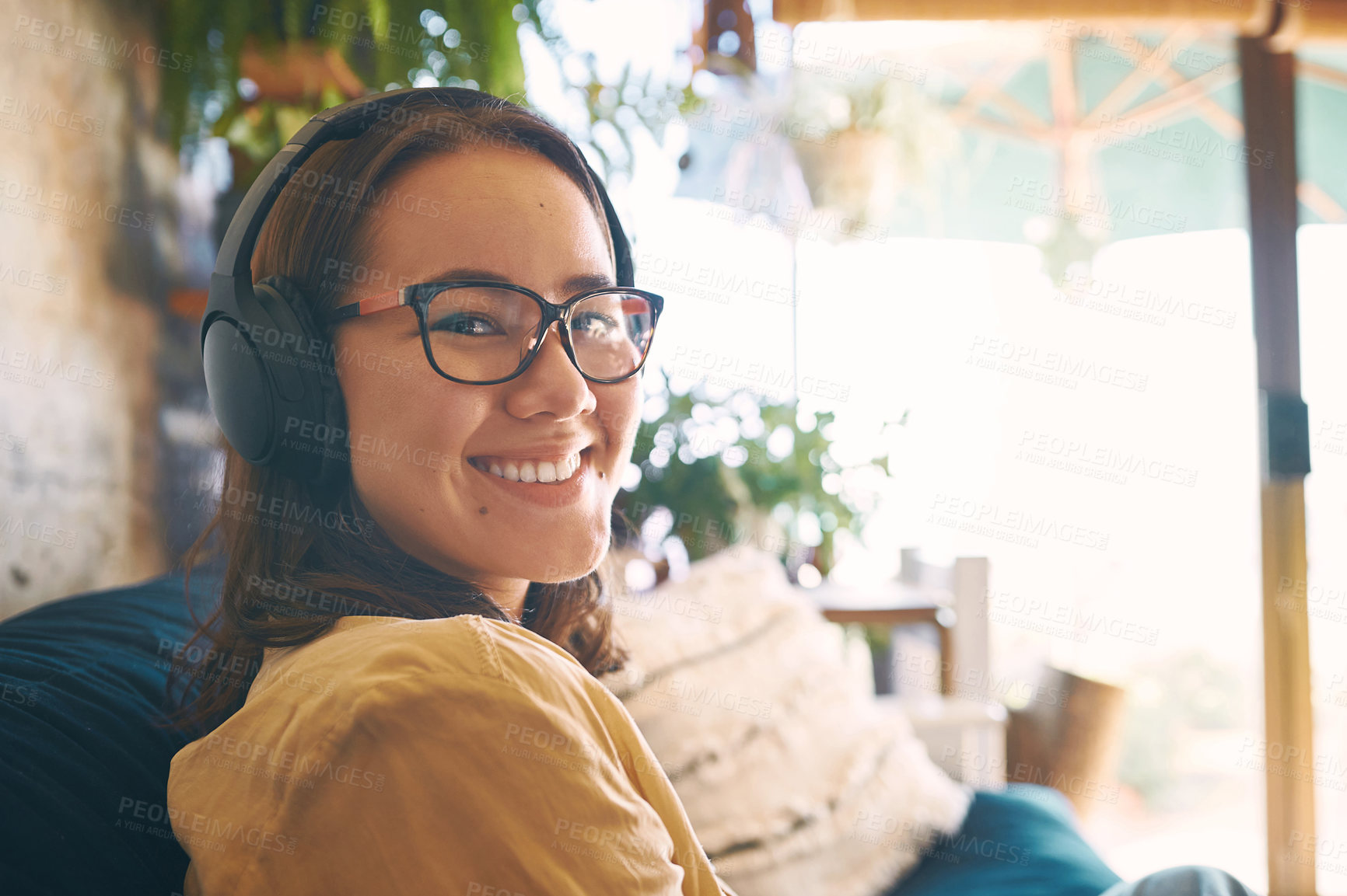 Buy stock photo Portrait of a young woman using headphones while relaxing on the sofa at home