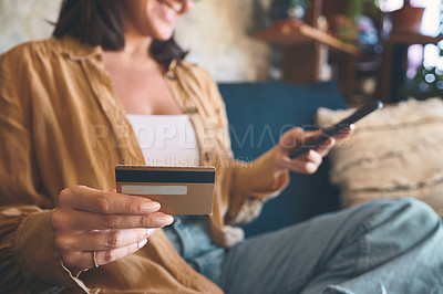 Buy stock photo Shot of an unrecognisable woman using a smartphone and credit card on the sofa at home