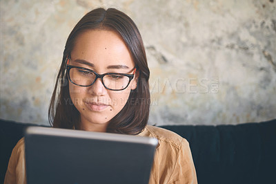 Buy stock photo Shot of a young woman using a digital tablet on the sofa at home