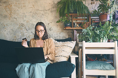 Buy stock photo Shot of a young woman using a laptop and credit card on the sofa at home