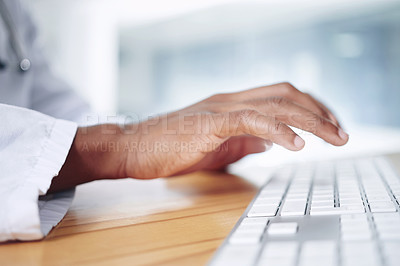 Buy stock photo Cropped shot of an unrecognizable doctor sitting alone in his office at the clinic and typing on a keyboard