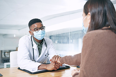 Buy stock photo Shot of a young doctor sitting with his patient and wearing a face mask while comforting her in the clinic