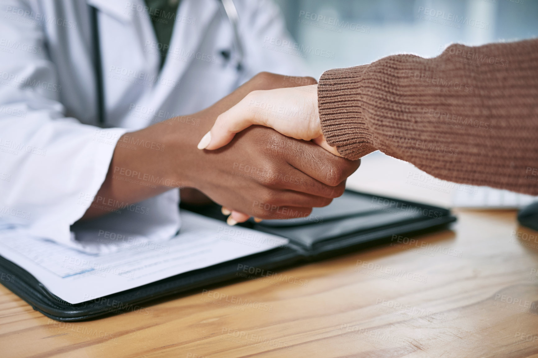 Buy stock photo Cropped shot of an unrecognizable doctor sitting and shaking hands with his patient during a consultation in the clinic