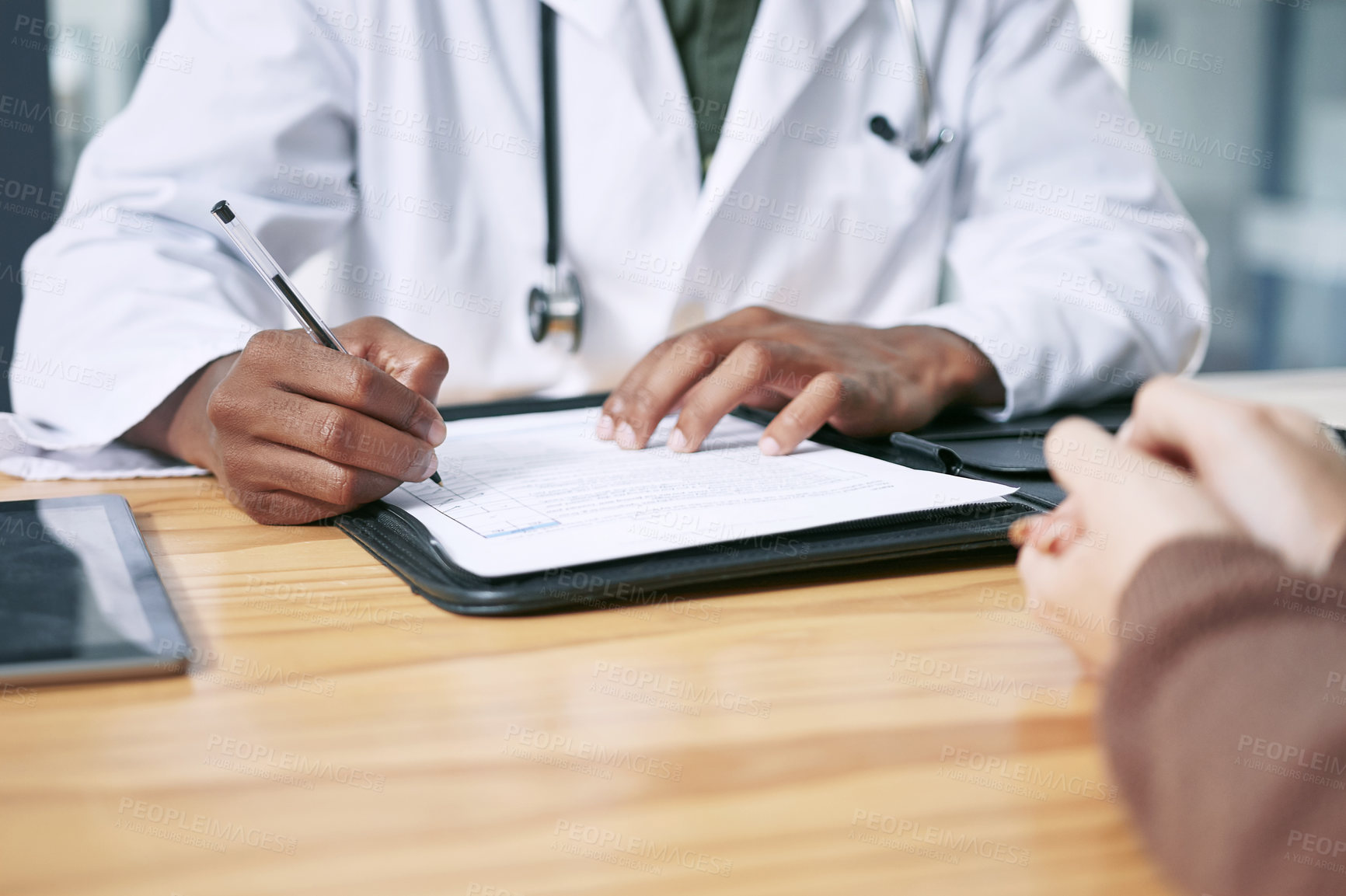 Buy stock photo Cropped shot of an unrecognizable doctor sitting with his patient and writing a prescription during a consultation in the clinic