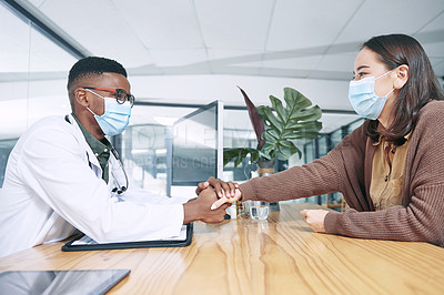 Buy stock photo Shot of a young doctor sitting with his patient and wearing a face mask while comforting her in the clinic