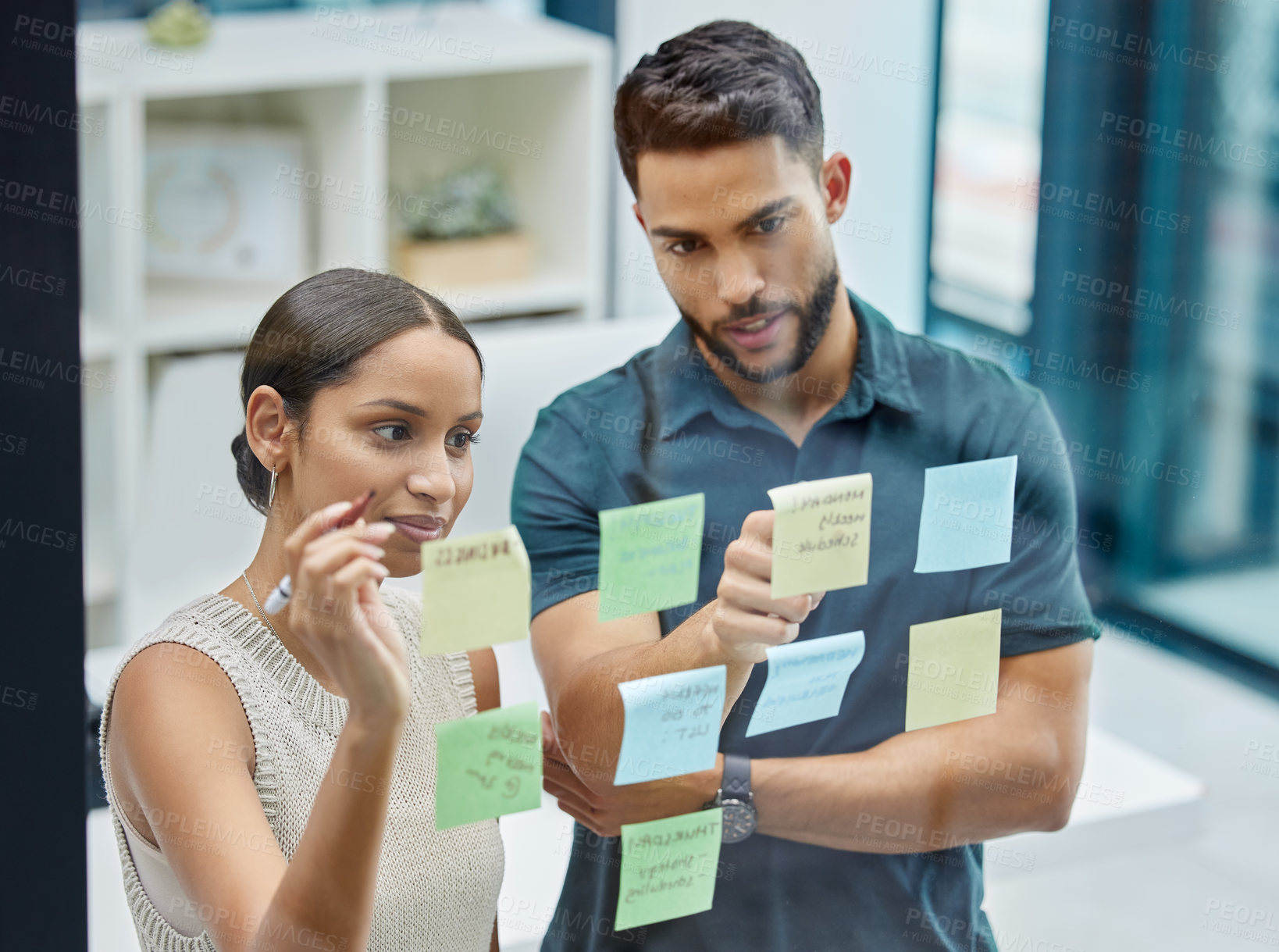 Buy stock photo Shot of two businesspeople brainstorming with sticky notes on a transparent wall