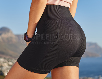 Buy stock photo Closeup shot of an unrecognizable and athletic young woman in running shorts taking a break during her run in the mountains