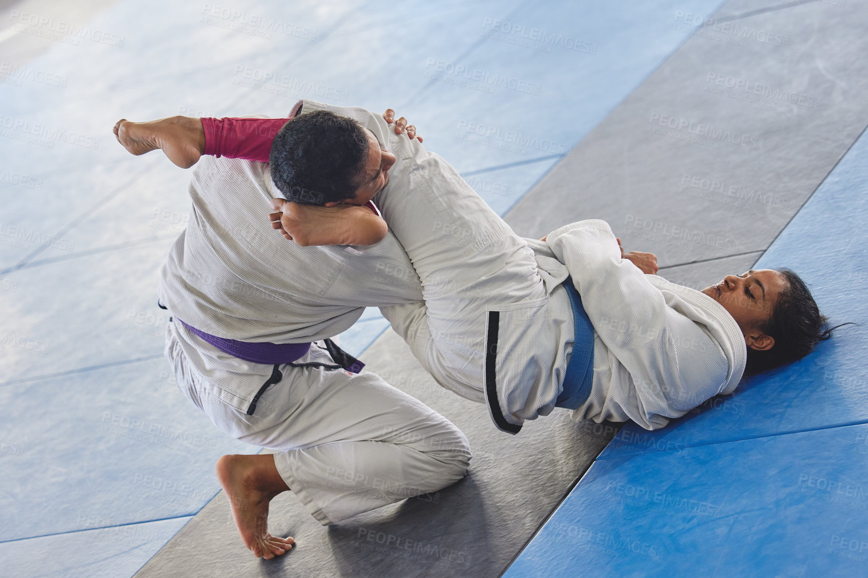 Buy stock photo Full length shot of two young martial artists practicing jiu jitsu in the gym