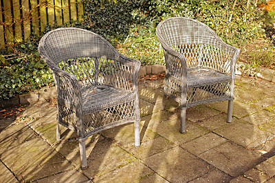 Buy stock photo Woven armchairs outside in a rustic garden with green plants for relaxing after gardening. Yard landscape with two wooden chairs in nature in a backyard patio to enjoy the sun on a warm winter day