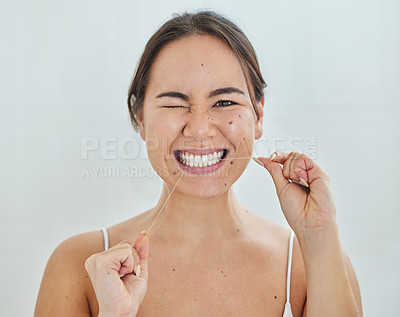 Buy stock photo Shot of a young woman flossing her teeth in a bathrroom at home