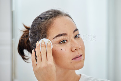 Buy stock photo Shot of a young woman cleaning her face with a cotton pad in a bathroom at home