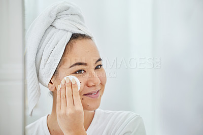 Buy stock photo Shot of a young woman cleaning her face with a cotton pad in a bathroom at home