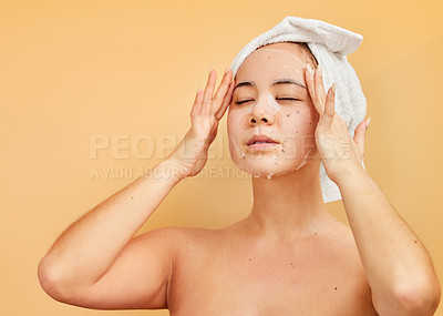 Buy stock photo Shot of a young woman applying a face mask during her morning beauty routine against a yellow background