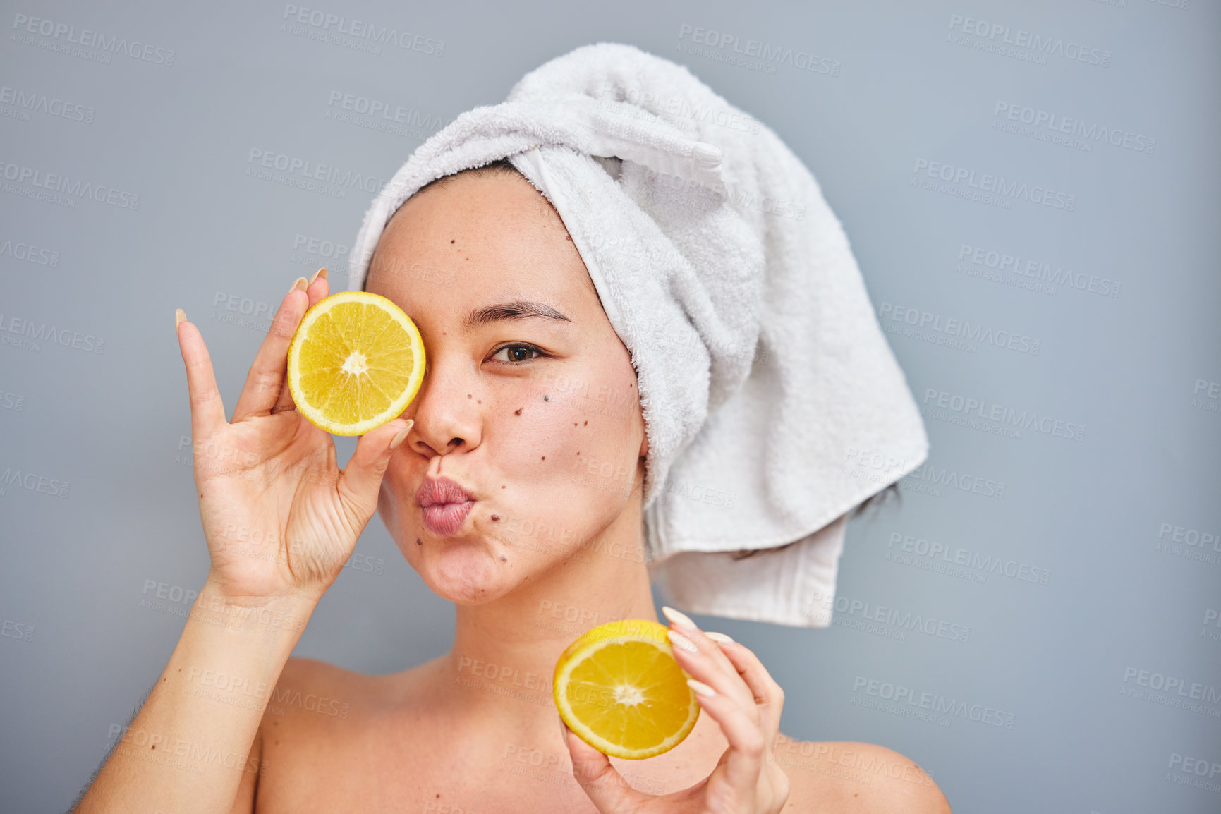 Buy stock photo Shot of a young woman holding lemon halves against a grey background