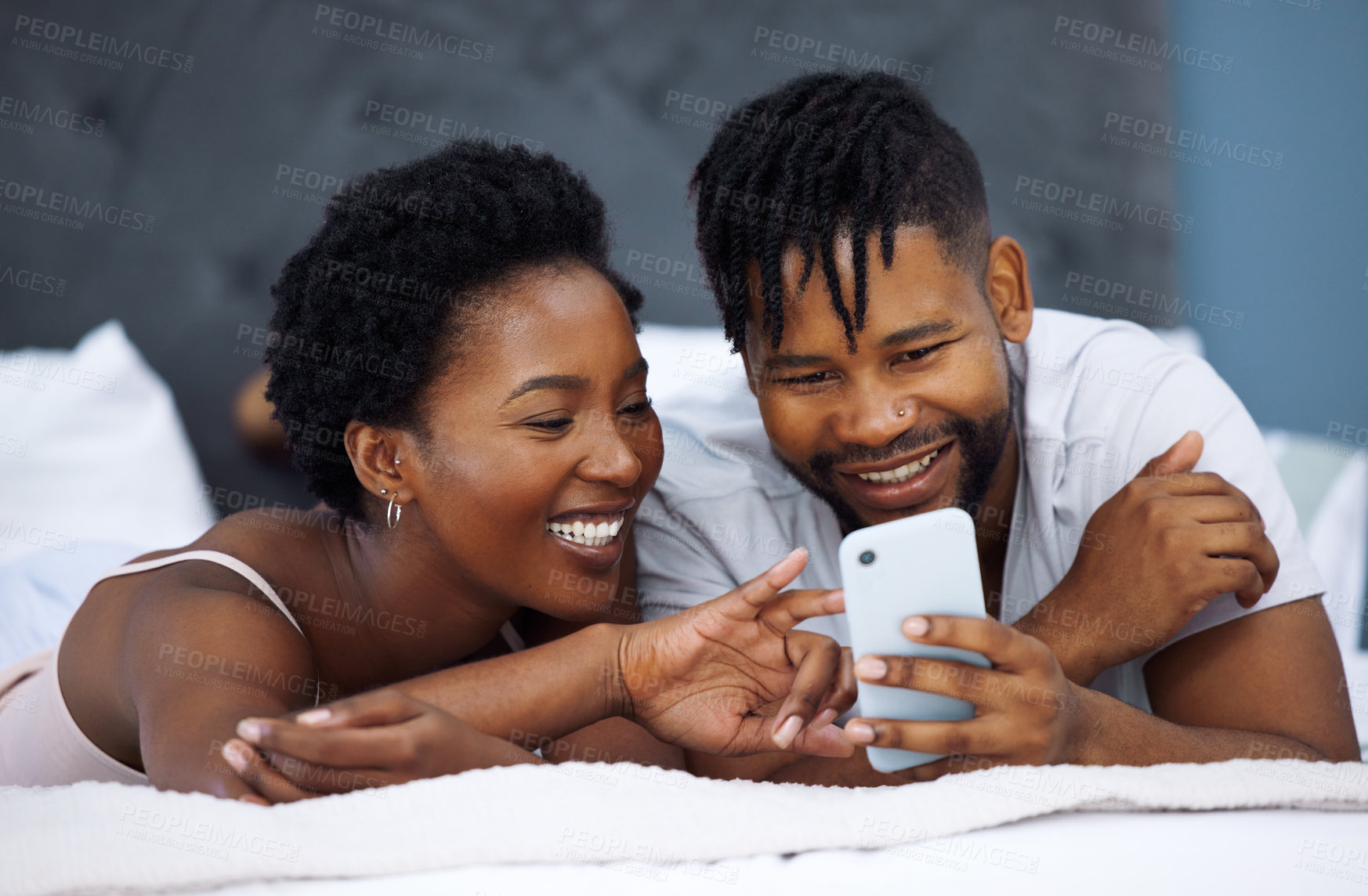 Buy stock photo Morning, smartphone and black couple lying on bed for social media, connection or relax in bedroom. Online, romantic man and happy woman with love for text, browsing internet or weekend rest in home