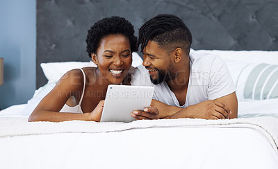 Buy stock photo Shot of a young couple using a digital tablet in bed at home