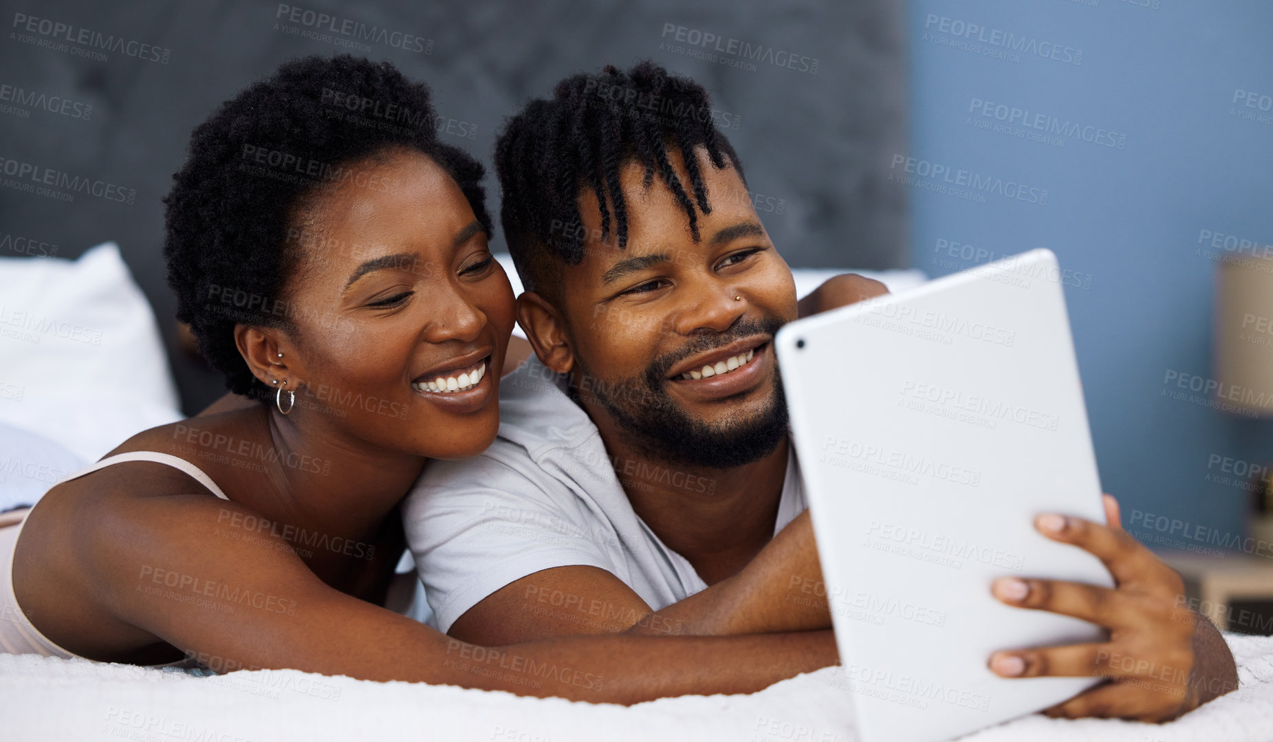 Buy stock photo Shot of a young couple using a digital tablet in bed at home