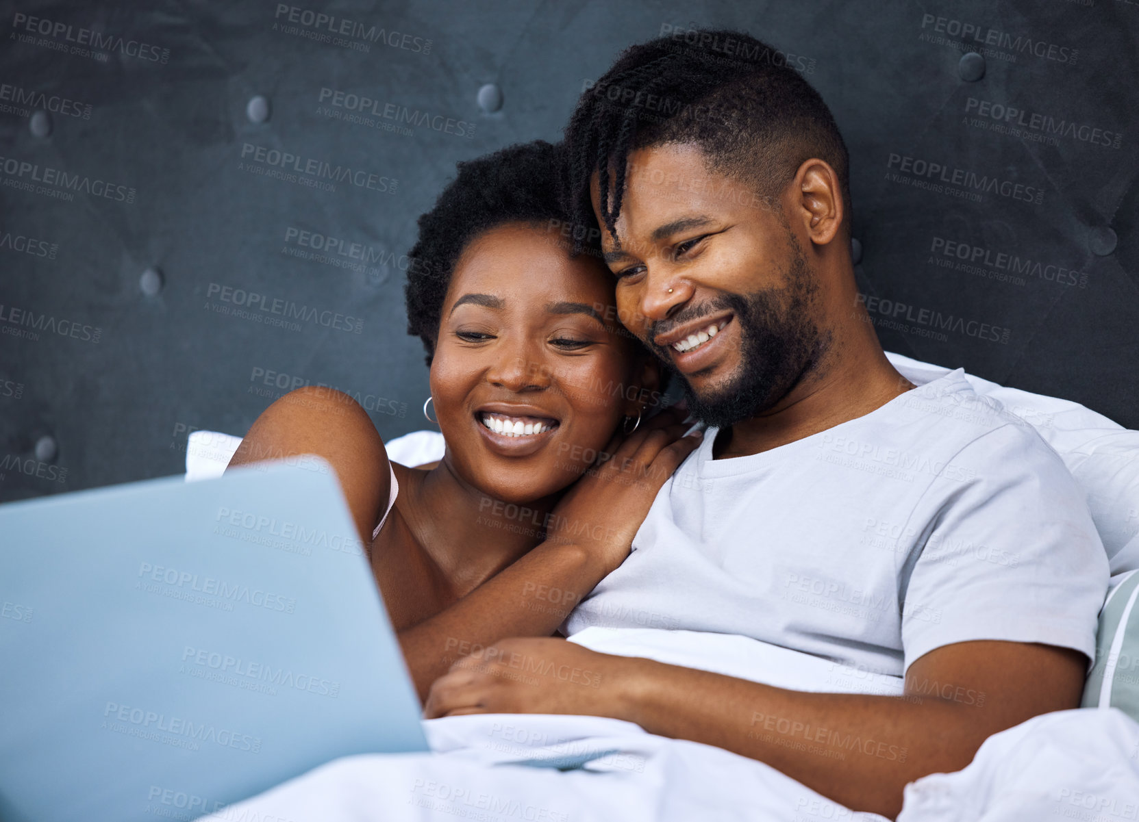 Buy stock photo Shot of a young couple using a laptop in bed at home
