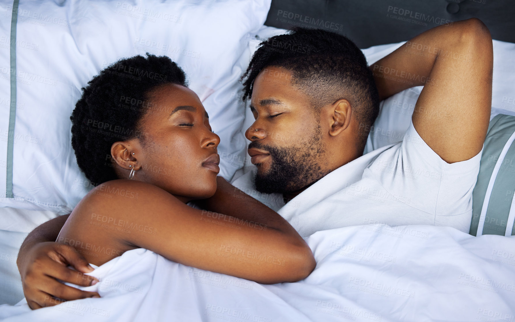 Buy stock photo Shot of a happy young couple sleeping in bed together at home