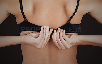 Buy stock photo Cropped studio shot of an unrecognizable woman removing her bra against a black background