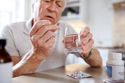 Buy stock photo Shot of an elderly man taking his medication at home