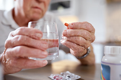 Buy stock photo Closeup shot of an elderly man taking medication while siting at the kitchen table at home