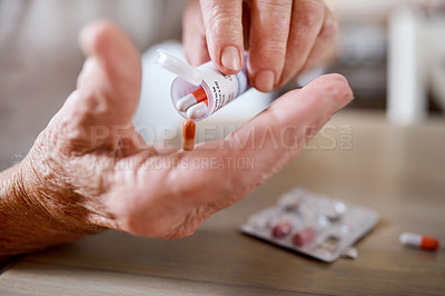 Buy stock photo Closeup shot of an unrecognizable elderly man taking medication at the kitchen table at home