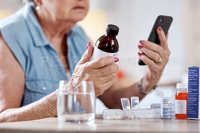 Buy stock photo Cropped shot of an unrecognizable woman using her smartphone to do research on medication at the kitchen table at home