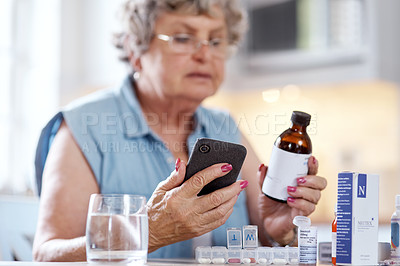 Buy stock photo Shot of an elderly woman using her cellphone to research medication at home
