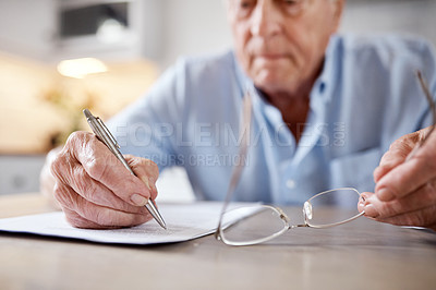 Buy stock photo Shot of an elderly man filling in forms at the kitchen table at home