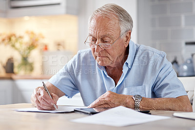 Buy stock photo Shot of an elderly man filling in forms at the kitchen table at home