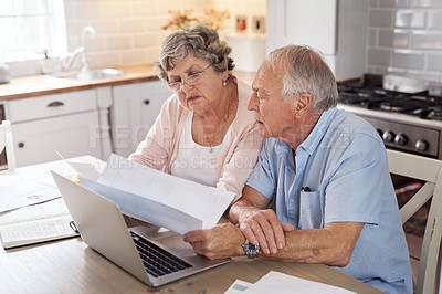 Buy stock photo Shot of an elderly couple using a laptop together in the kitchen at home