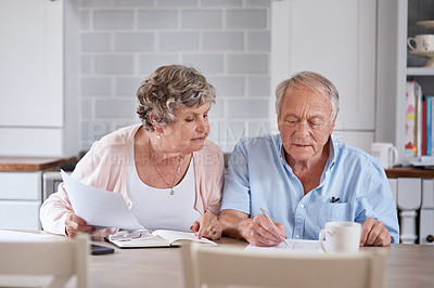 Buy stock photo Shot of an elderly couple going over paperwork together at the table at home