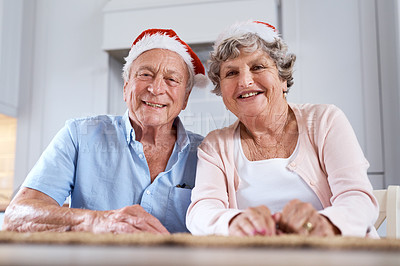 Buy stock photo Portrait of an elderly couple wearing festive hats at the table together at home