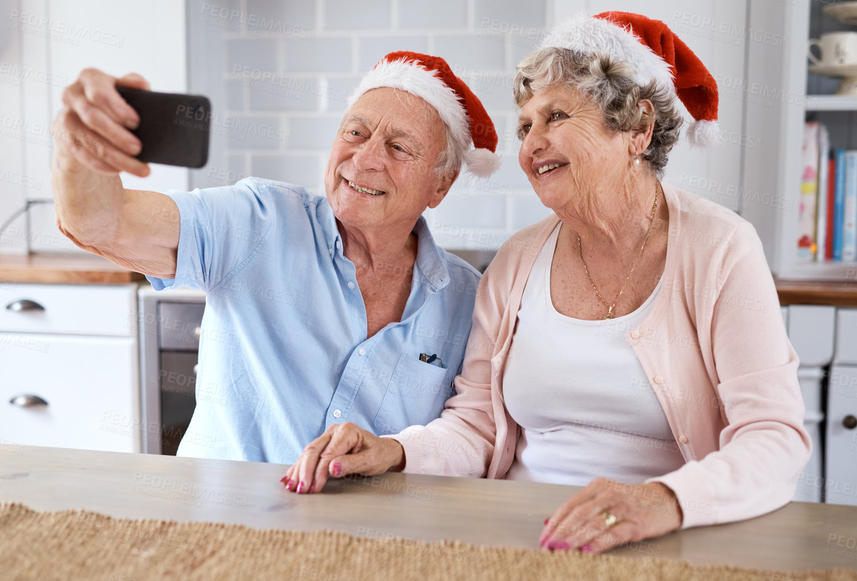 Buy stock photo Shot of an elderly couple taking a festive selfie at home