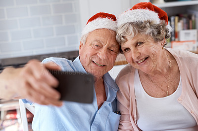 Buy stock photo Shot of an elderly couple taking a festive selfie at home