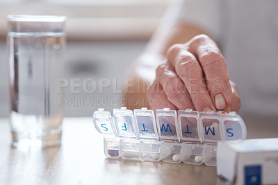 Buy stock photo Cropped shot of an unrecognizable elderly man arranging his medication at the table at home
