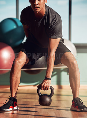 Buy stock photo Shot of a man working out in the gym using kettlebells