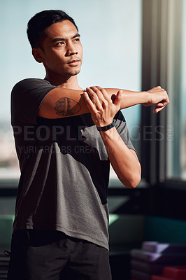 Buy stock photo Shot of a young man stretching his arms before a workout